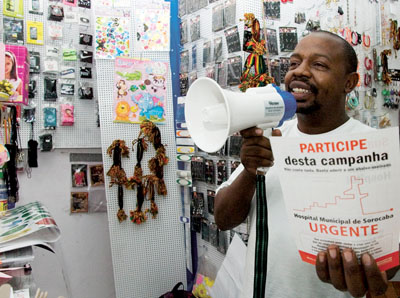 Fernando usa megafone em sua loja para divulgar a campanha do hospital municipal