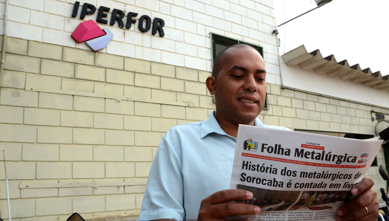 Na porta da fábrica, Willians Fagundes lê edição da Folha Metalúrgica no dia de sua reintegração